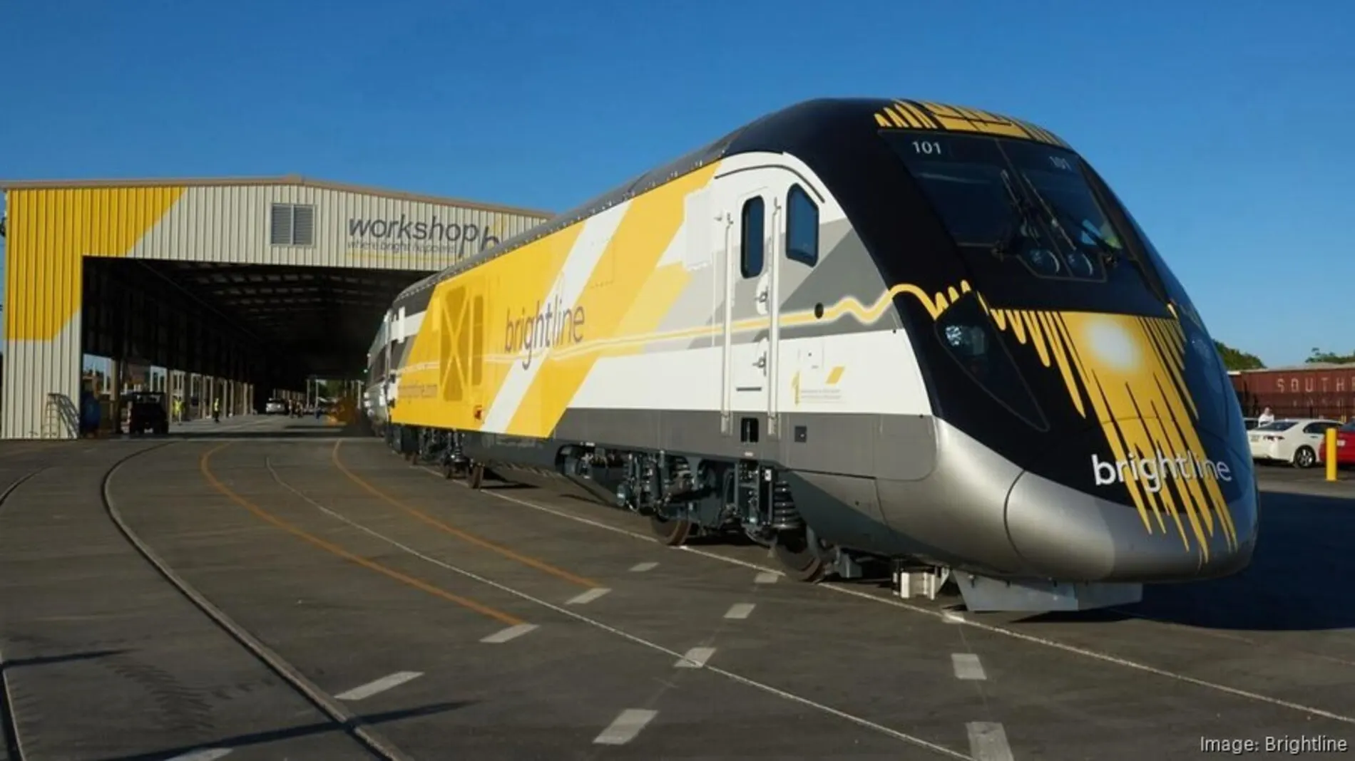 Brightline high-speed passenger train parked outside a modern maintenance facility in South Florida